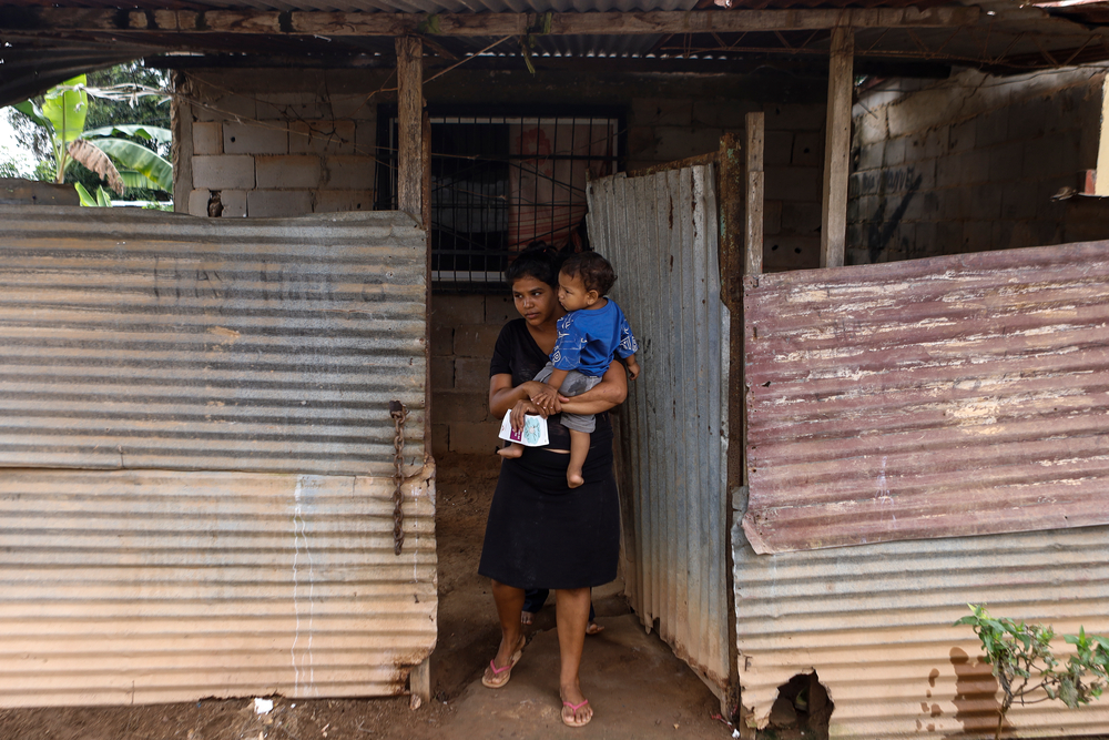 Frau mit Kind auf dem Arm vor ihrem Haus in Tumeremo, südliches Venezuela
