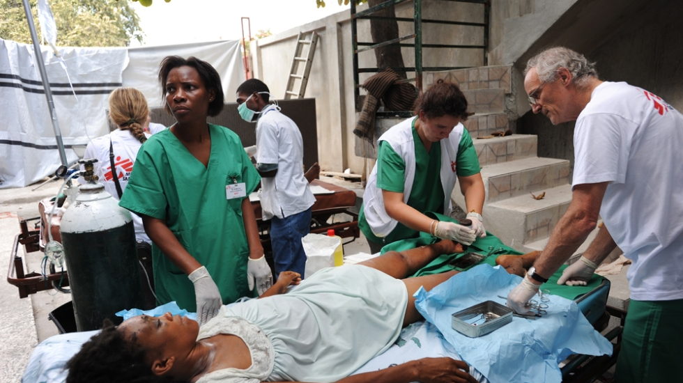 In Haiti liegt eine Frau auf einem Krankenhausbett, um sie herum Pflegepersonal von Ärzte ohne Grenzen
