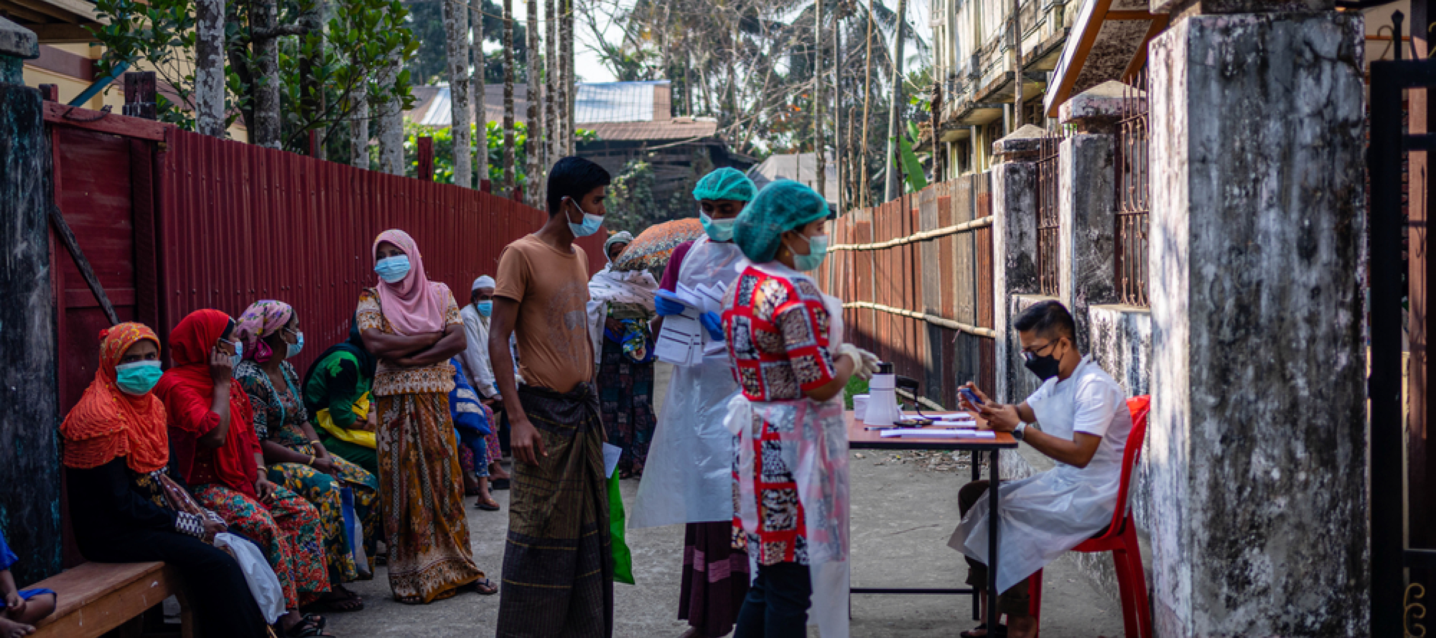 Patient*innen stehen am Eingang der mobilen Klinik in Aung Mingalar, Sittwe