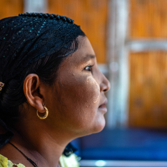 Foto des Profils der Patientin Khin Phyu Oo. Sie trägt goldenen Schmuck und blickt nach vorne